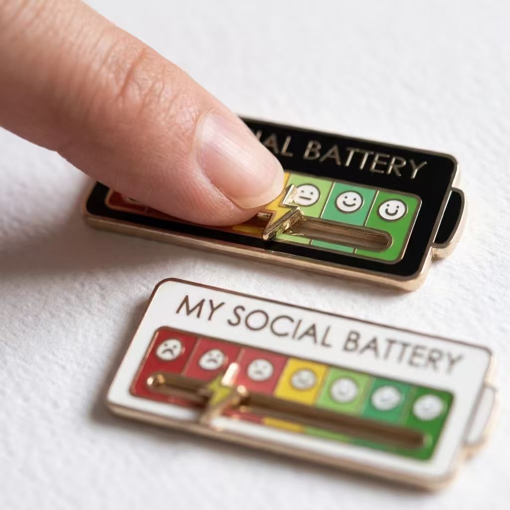 Colorful enamel pin featuring a funny social battery design, shown on a clean neutral background